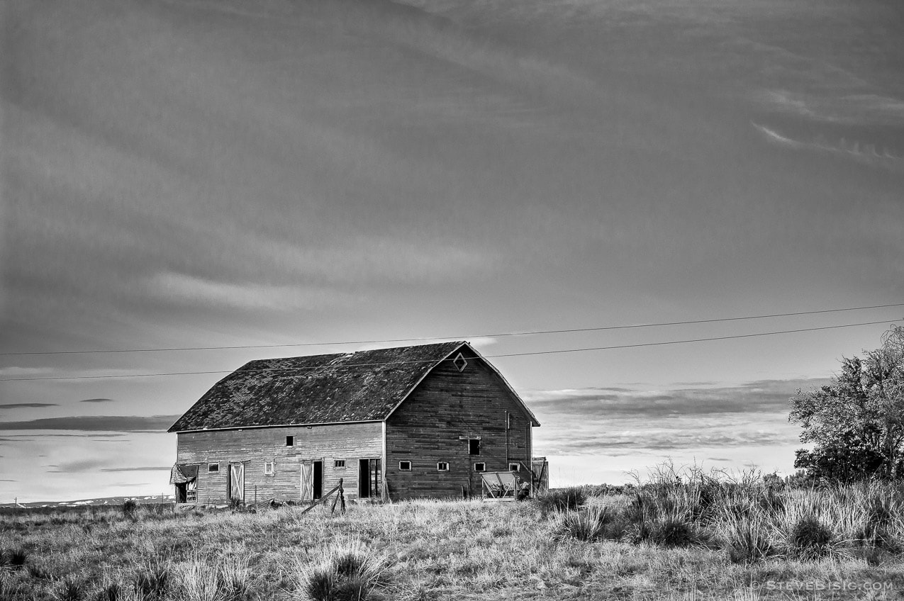 A black and white photograph of an abandoned barn on D Road NW in rural Douglas County, Washington.