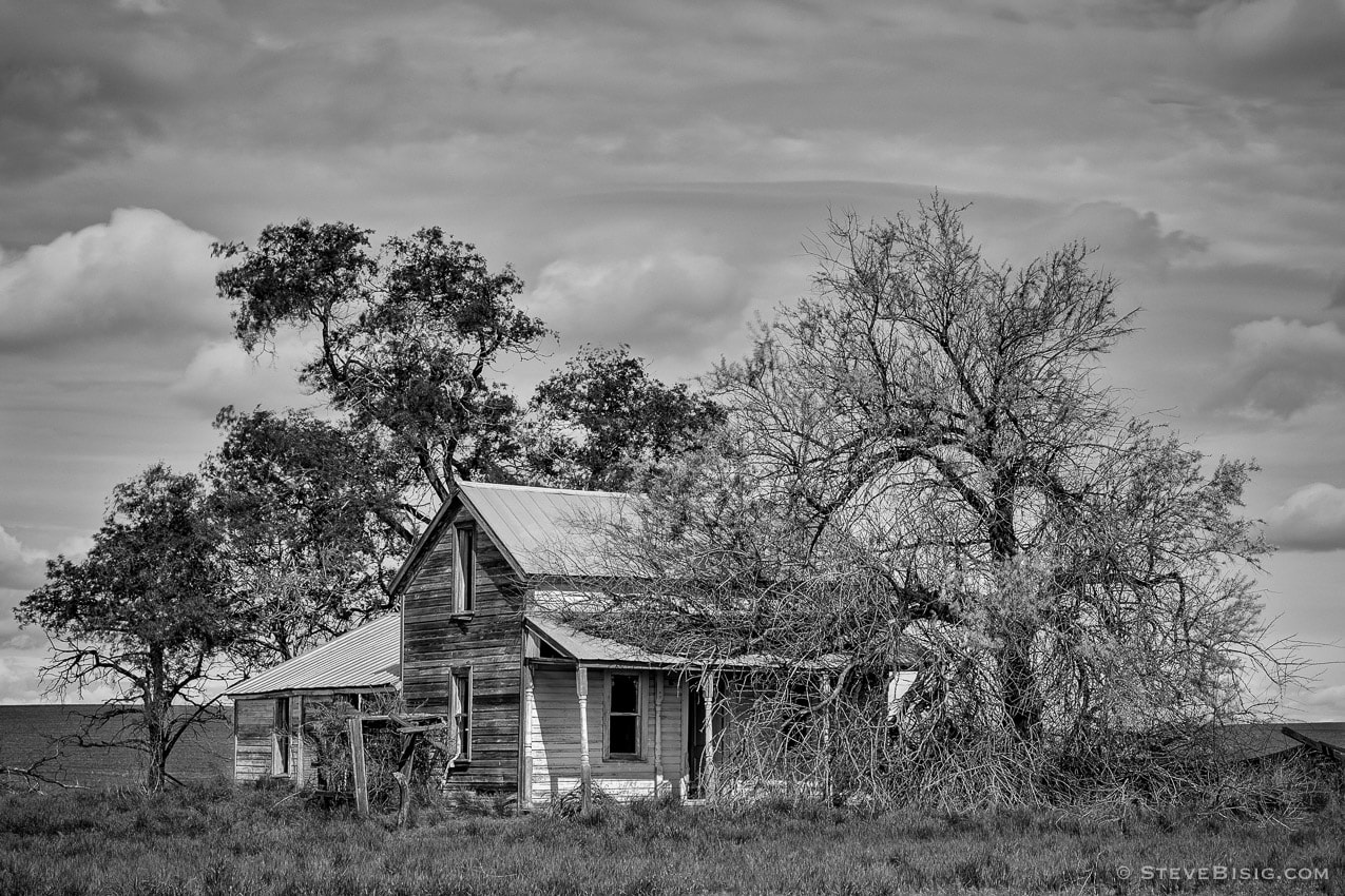 A black and white photograph of old abandoned farm house on A Road SW in rural Douglas County, Washington.