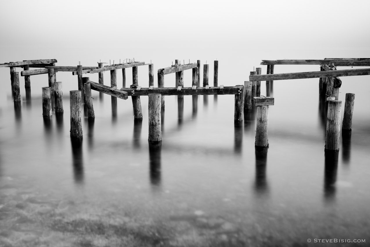 A black and white photograph of old dock pilings on the Puget Sound at Cummings Park, Tacoma, Washington.