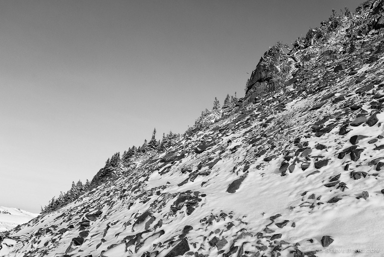A black and white photograph of a rocky hillside covered with fresh Autumn snow near Sunrise at Mount rainier National Park, Washington.