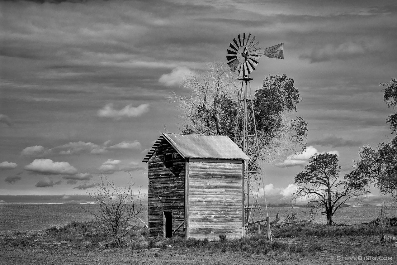 A black and white photograph of old windmill and outbuilding on A Road SW in rural Douglas County, Washington.