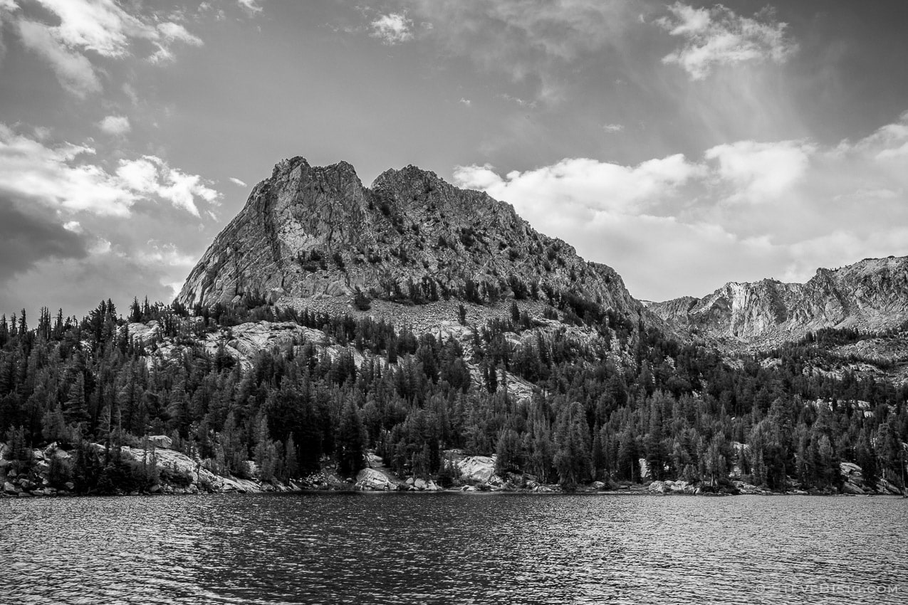 A black and white fine art landscape photograph of Crystal Craig towering over Crystal Lake near Mammoth Lakes, California.