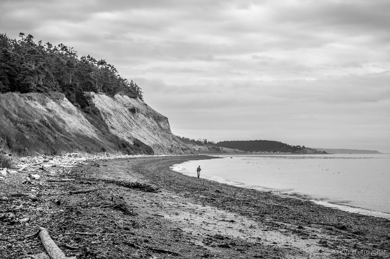 A black and white fine art photograph of a fisherman along the Puget Sound at Ebey's Landing on Whidbey island near Coupeville, Washington.