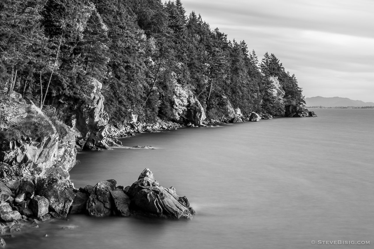 A long exposure black and white fine art photograph of the rocky coastline at Larrabee State Park in Whatcom County near Bellingham, Washington on a breezy Autumn evening just before sunset.