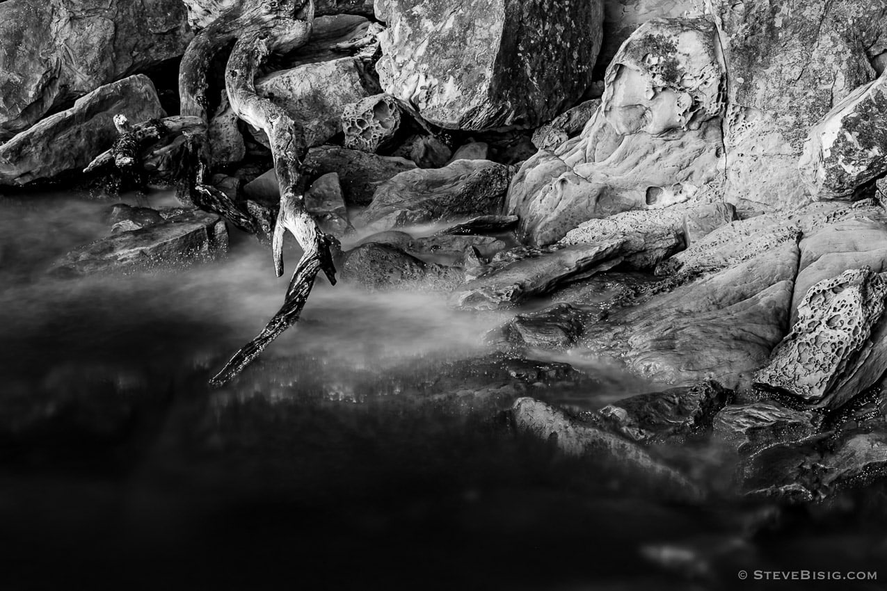 A long exposure fine art black and white photograph of sandstone formations at high tide along the coastline at Larrabee State Park in Whatcom County near Bellingham, Washington.