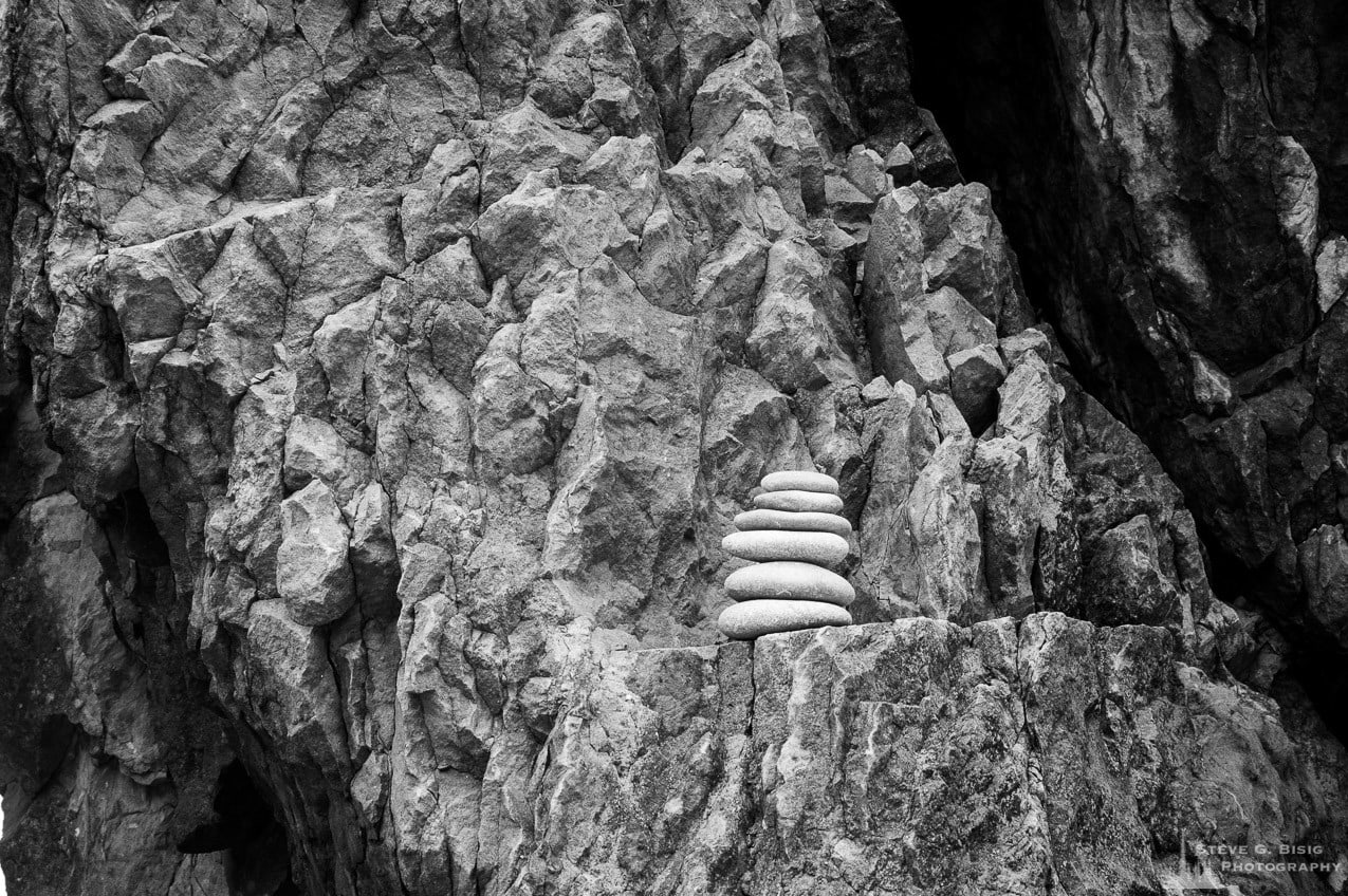 A black and white photo of a rock cairn sitting on a rock ledge at Ruby Beach in the Olympic National Park in Washington State.