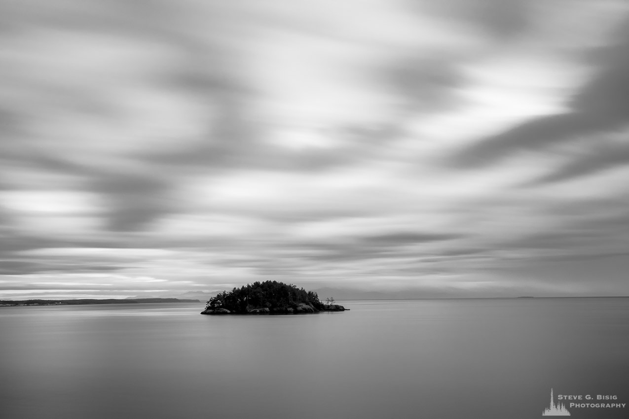 A black and white, long exposure landscape photograph of Deception Island as seen from Rosario Head at Deception Pass State Park on Fidalgo Island, Washington.