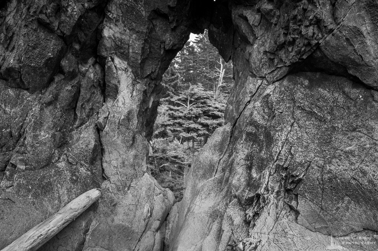 A black and white nature photograph of peep hole through a rock at Ruby Beach in the Olympic National Park in Washington State.
