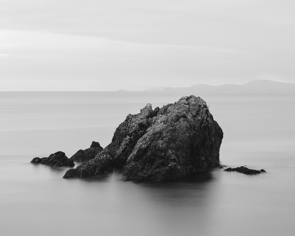 A black and white, long exposure landscape photograph of Urchin Rocks near Rosario Beach at Deception Pass State Park on Fidalgo Island, Washington.