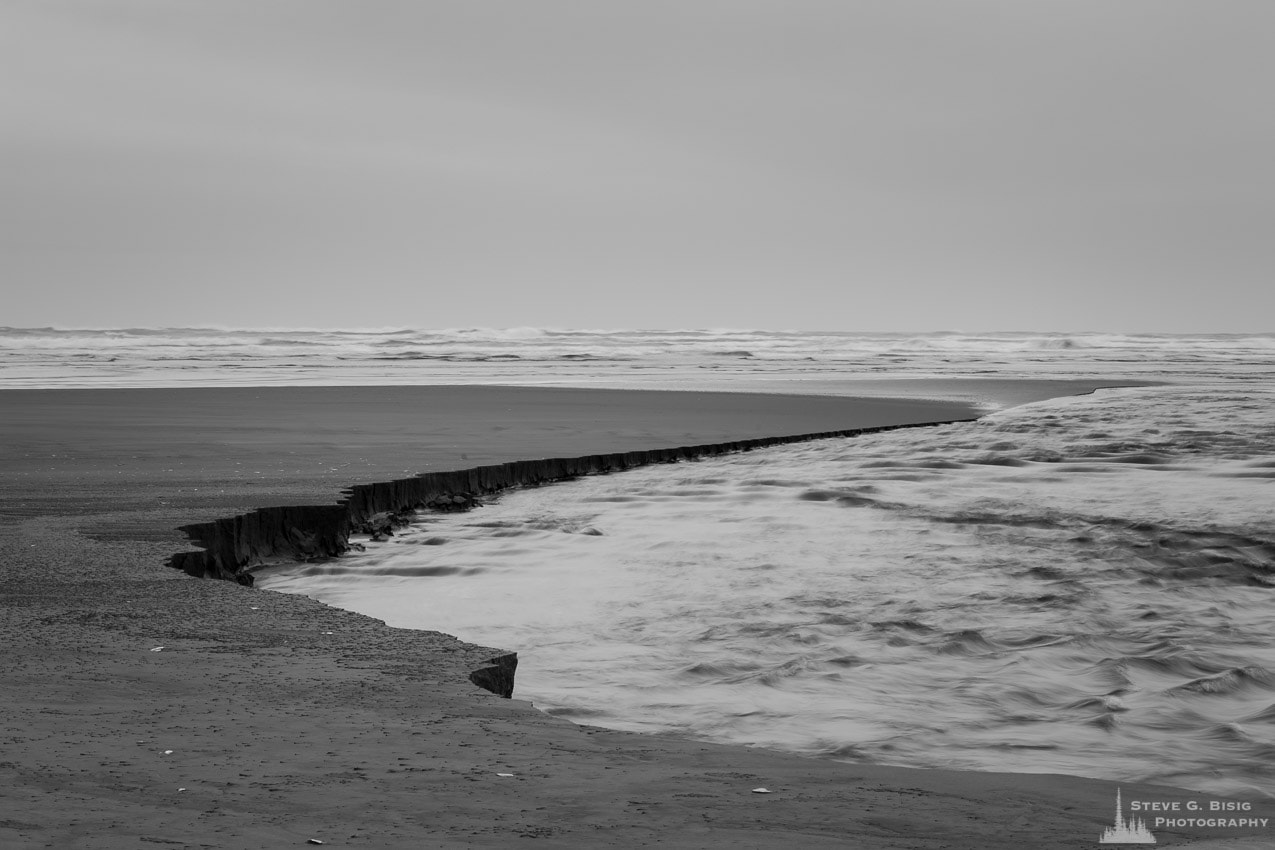 A black and white landscape photograph of Conner Creek as it empties into the Pacific Ocean at Copalis Beach, Washington.