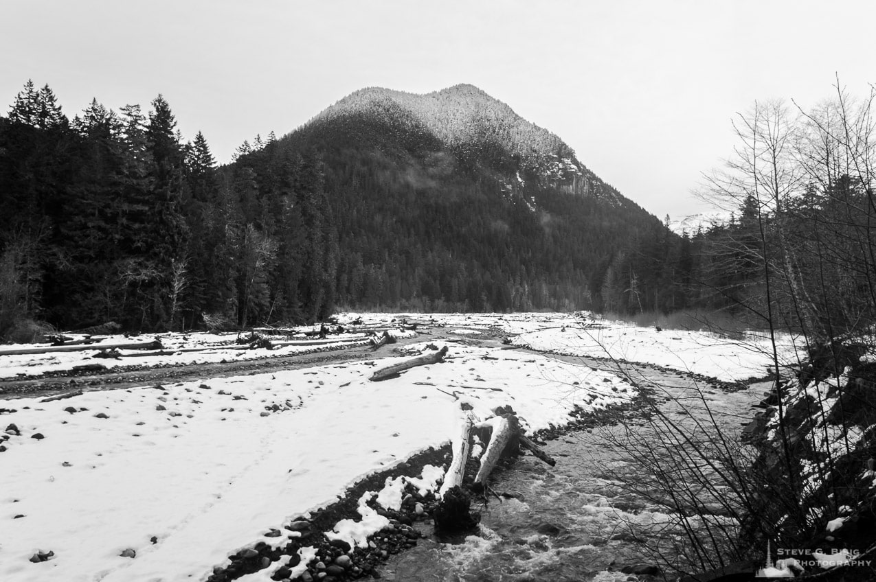 A black and white landscape photograph of the Carbon River in Mount Rainier National Park, Washington after a Winter snowfall.