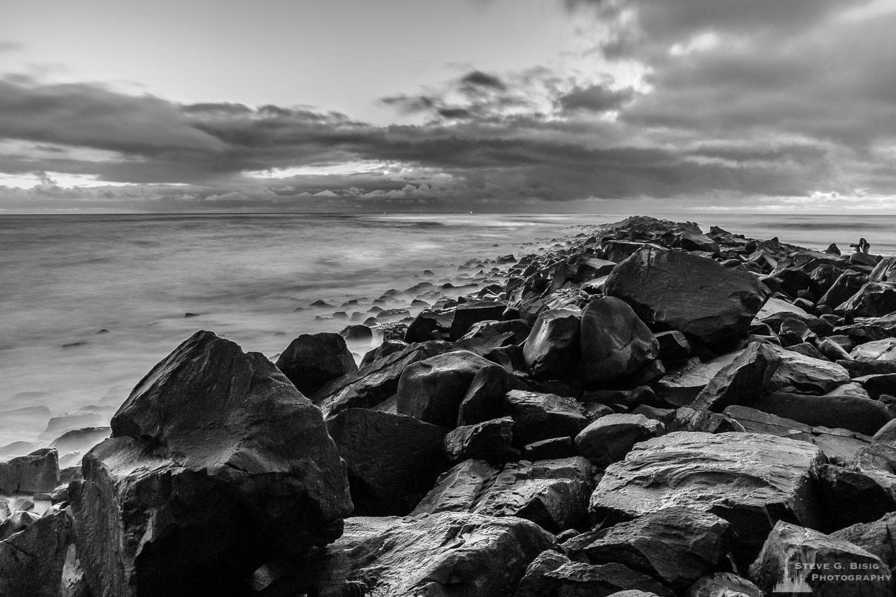 A black and white landscape photograph of the North Jetty of Grays Harbor at Ocean Shores, Washington on a cloudy winter night.