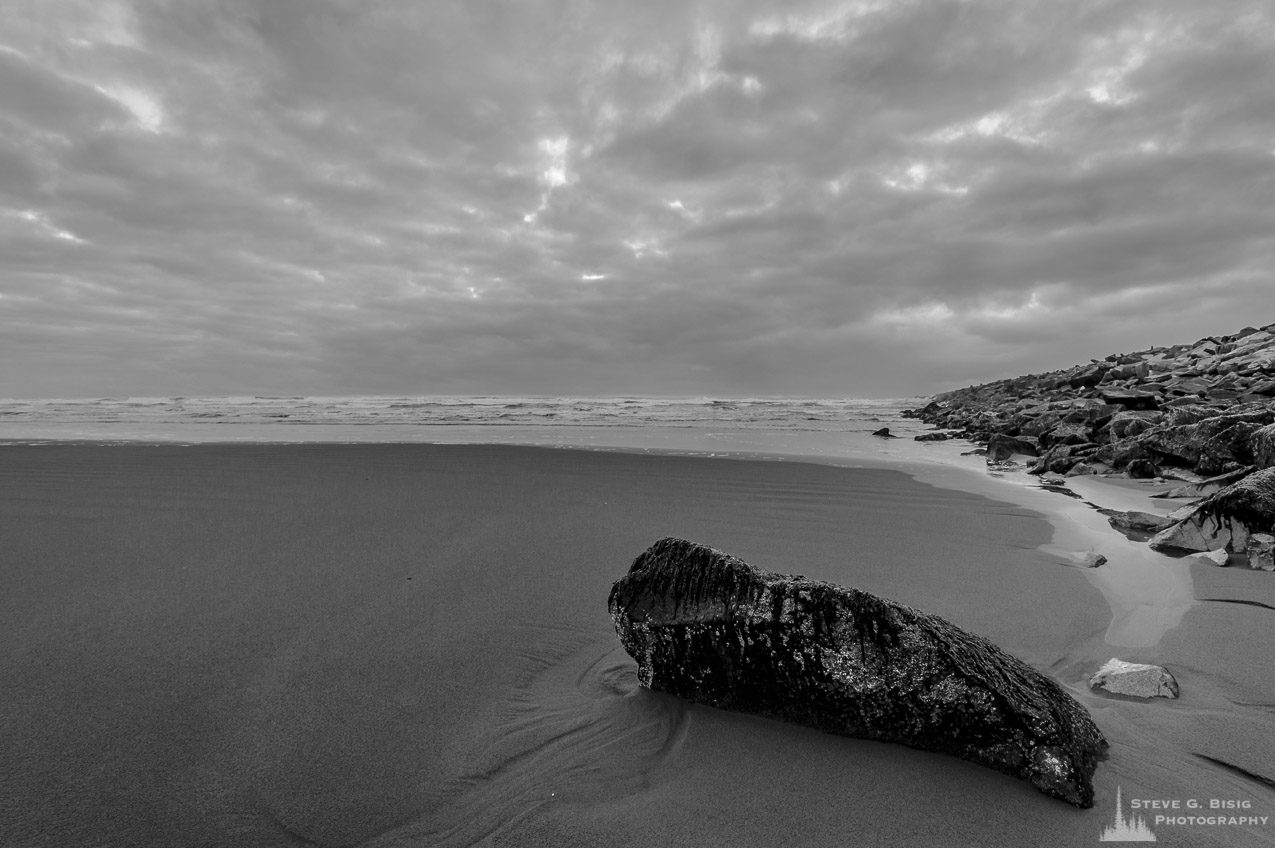 A black and white landscape photograph of the Pacific Ocean beach along the South Jetty of Grays Harbor at Westhaven State Park near Westport, Washington.