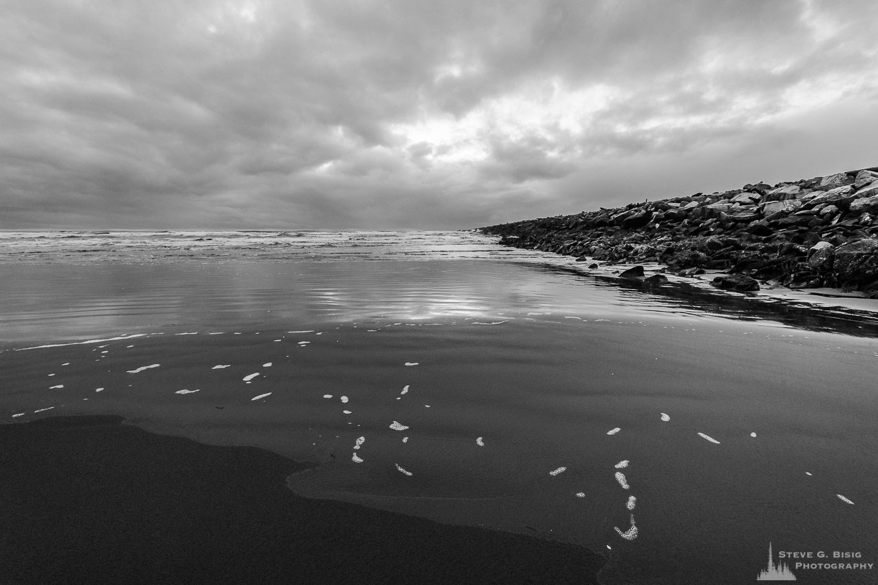 A black and white landscape photograph of the Pacific Ocean surf and beach along the South Jetty of Grays Harbor at Westhaven State Park near Westport, Washington.