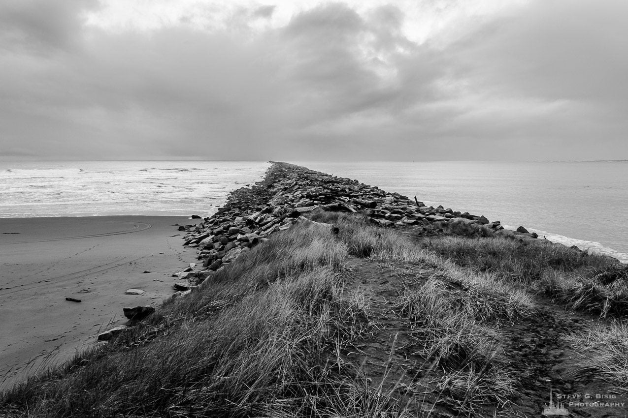 A black and white landscape photograph of the South Jetty between the Pacific Ocean and Grays Harbor at Westhaven State Park near Westport, Washington.