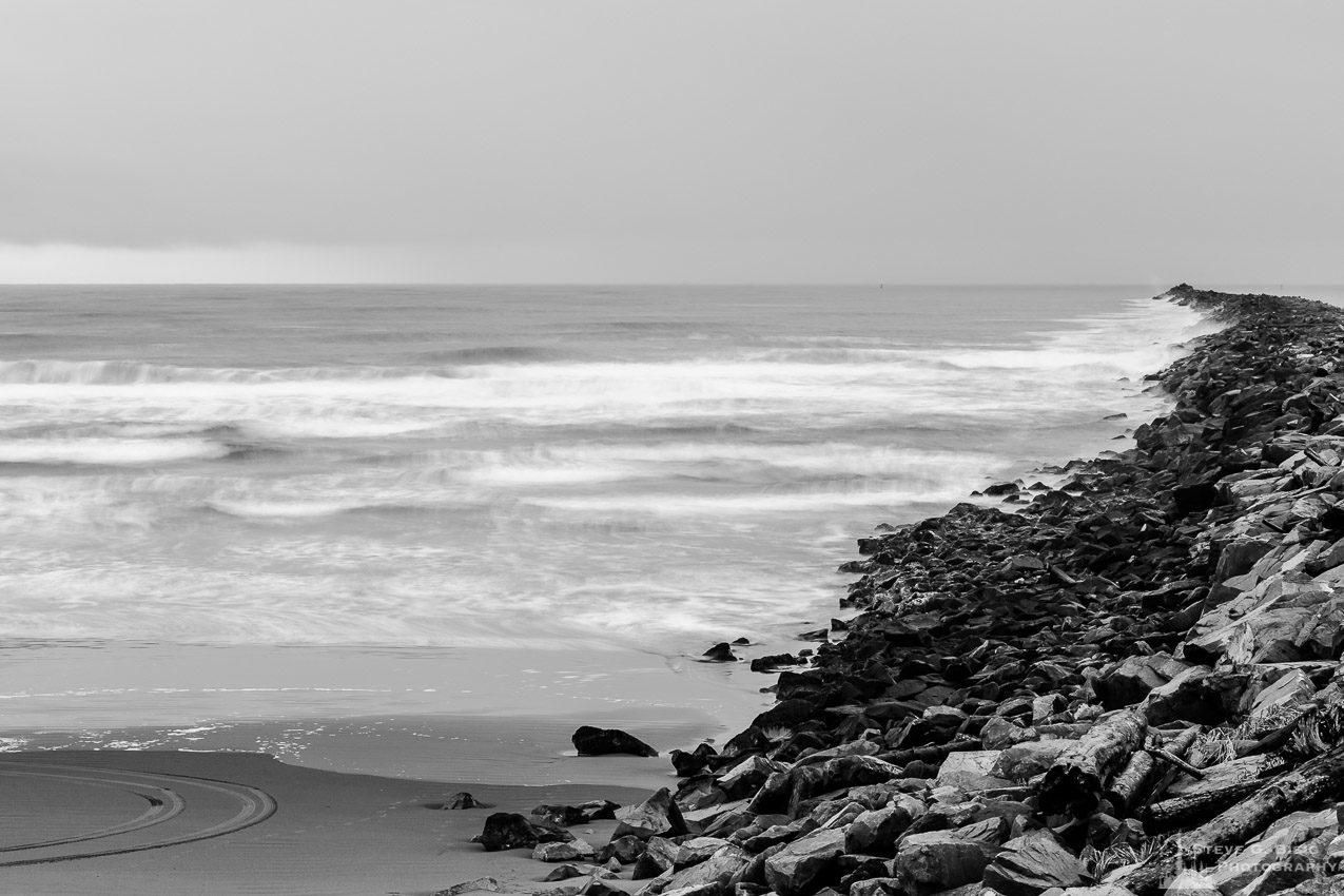 A black and white long exposure landscape photograph of the Pacific Ocean and beach along the South Jetty of Grays Harbor at Westhaven State Park near Westport, Washington.