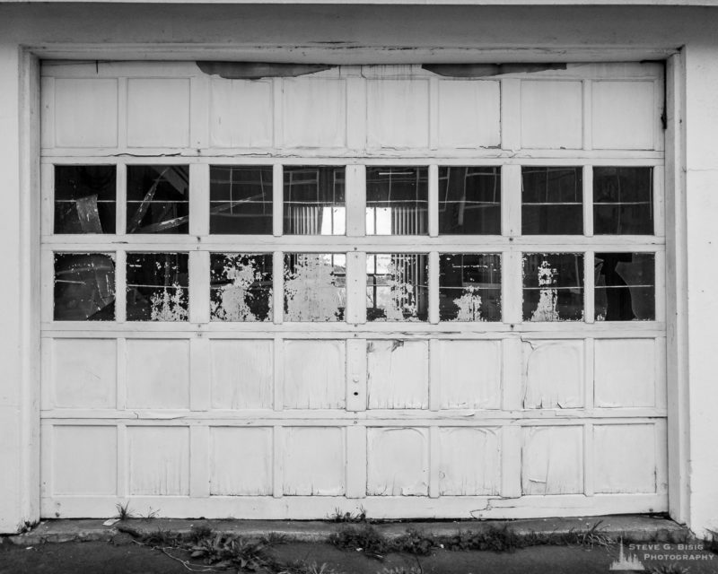 A black and white mobile urban photograph of an old roll-up door on a vacant building in Oak Harbor, Washington.