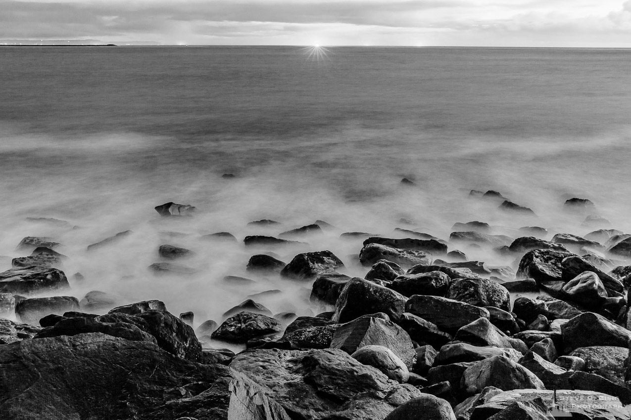 A black and white landscape photograph of the Pacific Ocean at the North Jetty of Grays Harbor at Ocean Shores, Washington on a cloudy winter night.