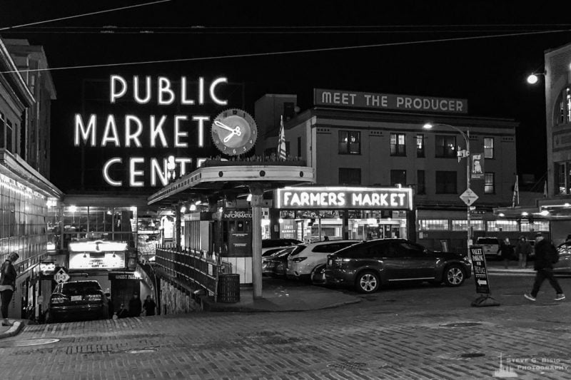 A black and white mobile street photograph of the Pike Place Market in Seattle, Washington after dark on a Winter night.