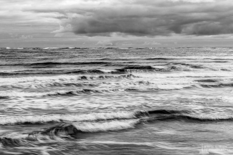 A long exposure black and white landscape photograph of the waves of the Pacific Ocean at North Cove, Washington.