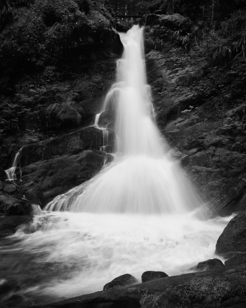 A black and white landscape photograph of a waterfall found along Forest Road 52 (Skate Creek Road) in the Gifford Pinchot National Forest, Washington.