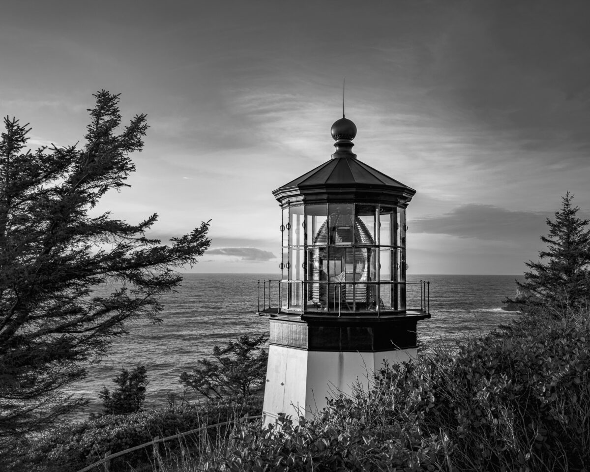 A black and white fine art photograph of the evening light shining on the Cape Meares Lighthouse near Tillamook, Oregon.
