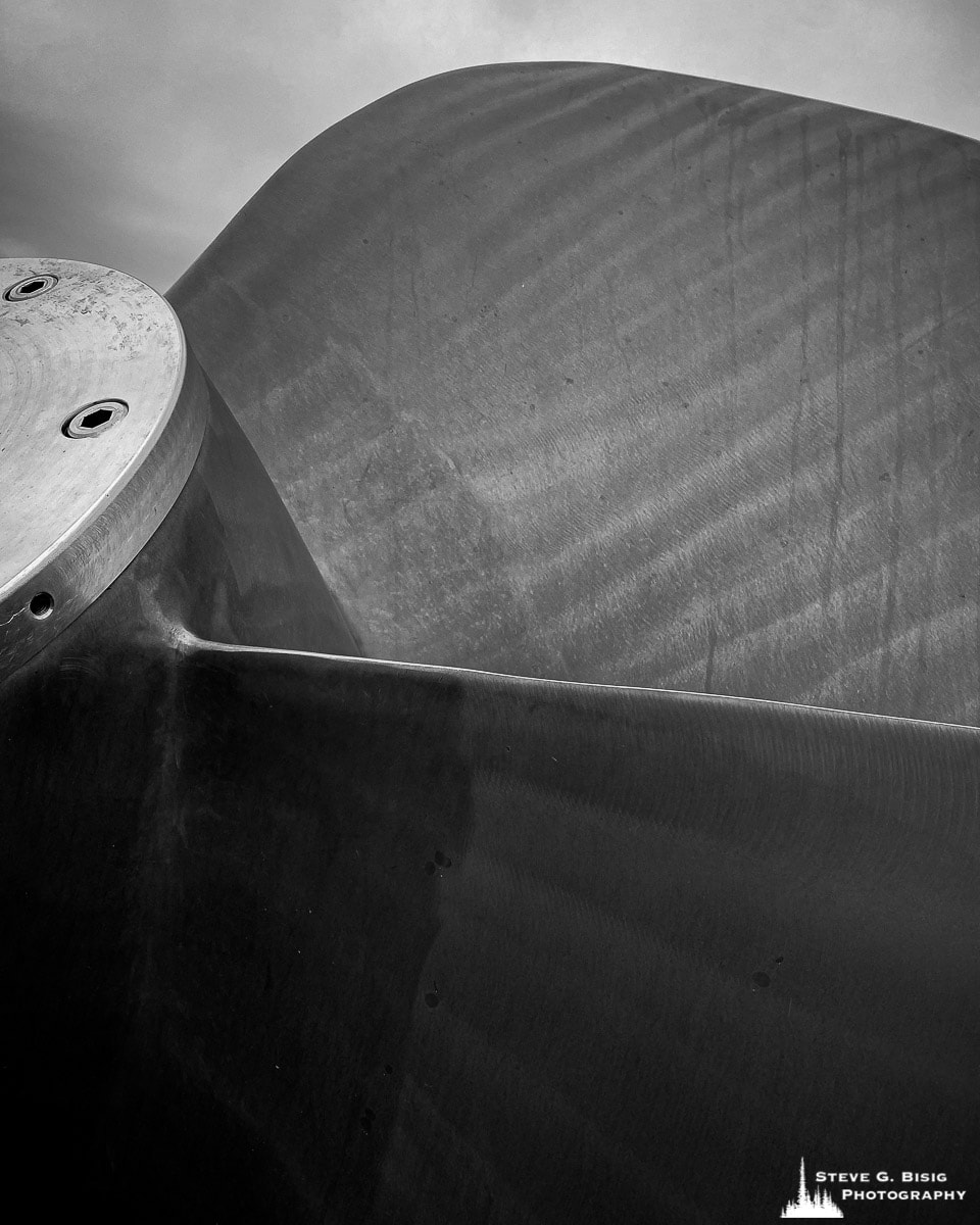 A close-up black and white mobile photograph of a ship propeller on display at the Columbia River Maritime Museum in Astoria, Washington.