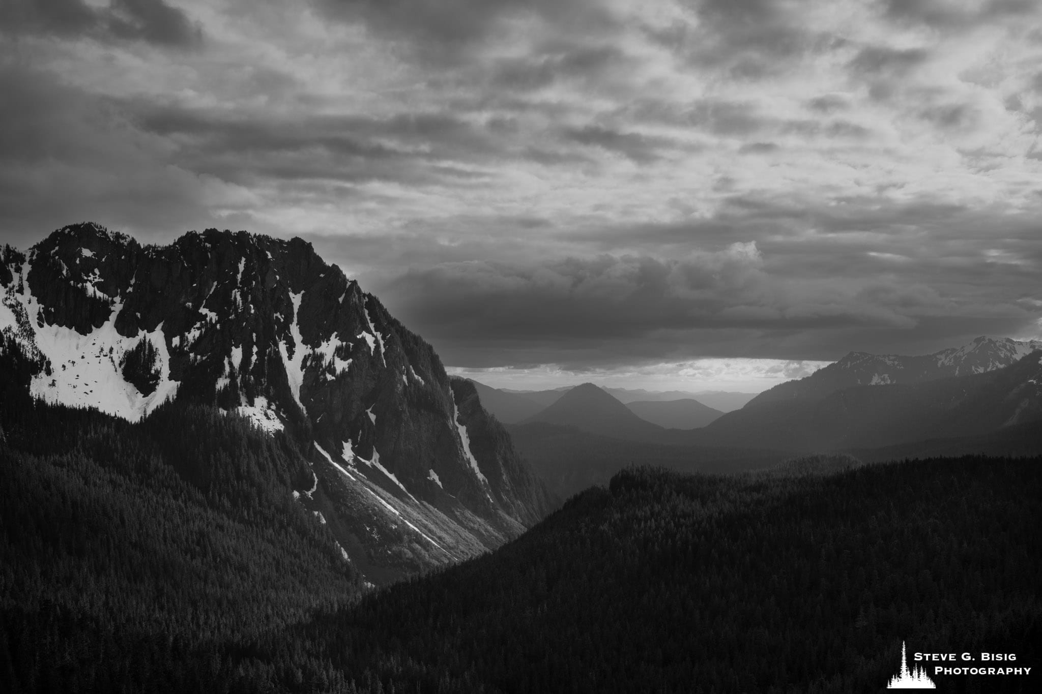 A black and white landscape photograph of the Nisqually River Valley as viewed from the Inspiration Point Overlook at Mt. Rainier National Park, Washington.
