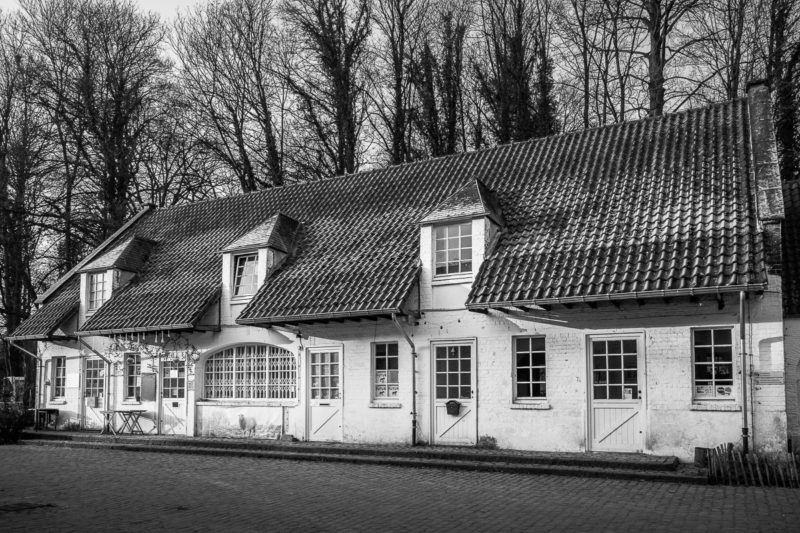A black and white photograph of the old agricultural buildings at Rouge Cloître, Auderghem, Belgium.