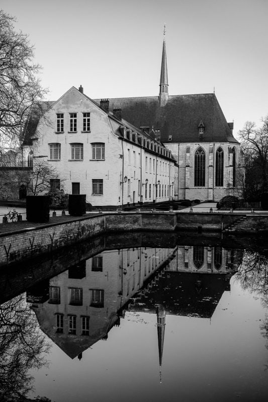 A black and white photograph of the Abbaye de La Cambre reflecting into a pond in Brussels, Belgium.