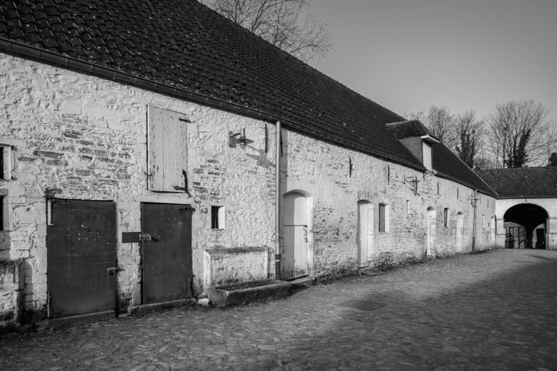 A black and white photograph of the agricultural buildings at Rouge Cloître in Auderghem, Belgium.