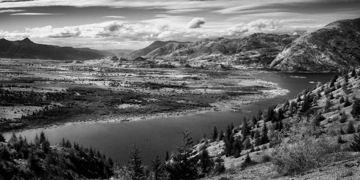 A black and white panoramic landscape photograph of Spirit Lake and the pumice plains of Mt . St. Helens from Windy Ridge in Skamania County, Washington.