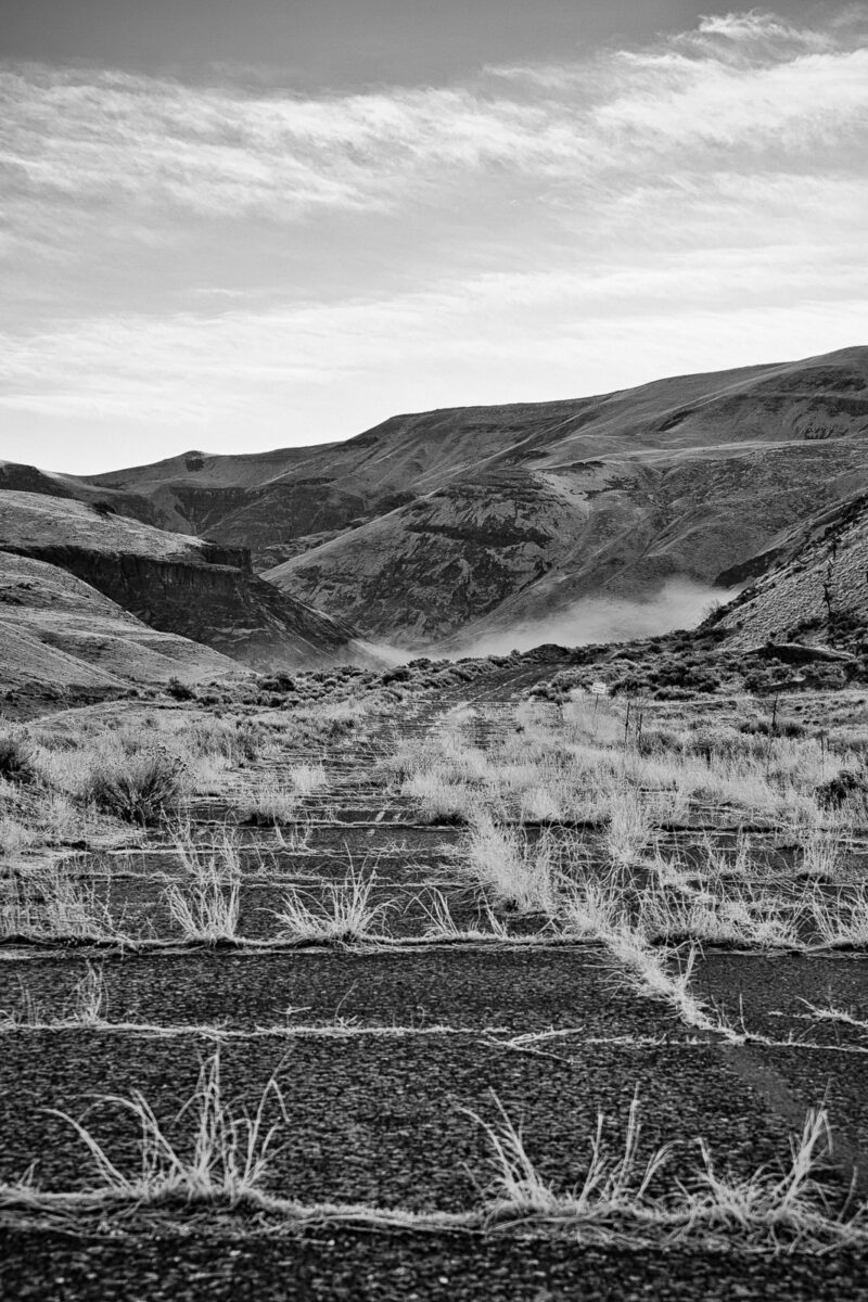 A black and white photograph of an abandoned section of old US 97 (now near SR 821) that used to route through the Yakima River Canyon in Yakima County near Selah, Washington before I-82 was constructed.