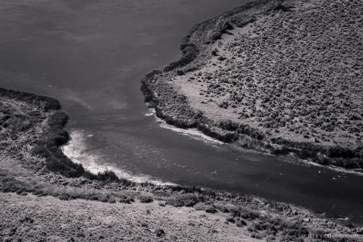 A black and white photograph of the shoreline  around Dry Falls Lake in the Upper Grand Coulee, Washington.