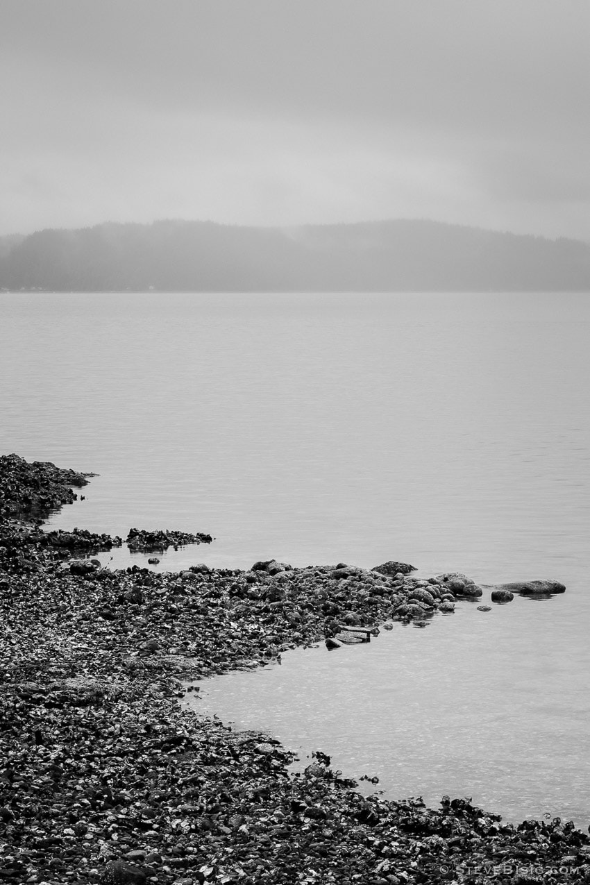 A black and white photograph of the rocky beach along Hood Canal at the Triton Cove State Park near Brinnon, Washington.