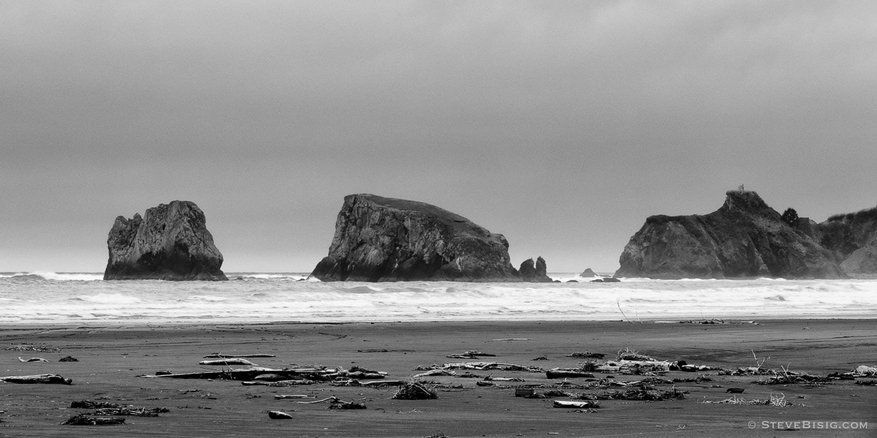 A black and white photograph of seastacks, Point Grenville and the Pacific Ocean as viewed from the beach along the Washington Coast. 