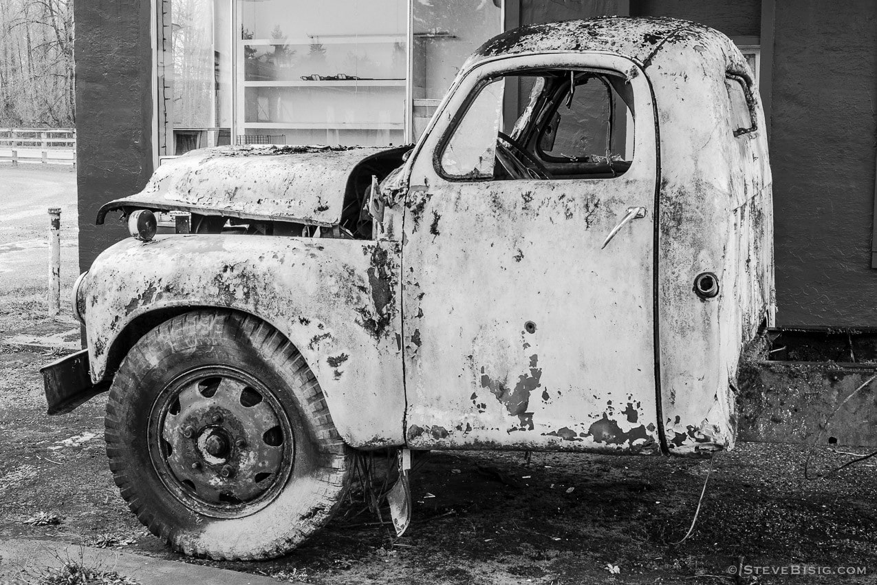 A black and white photograph of a rusty Studebaker truck sitting in an old gas station in the small Lewis County town of Pe Ell, Washington.