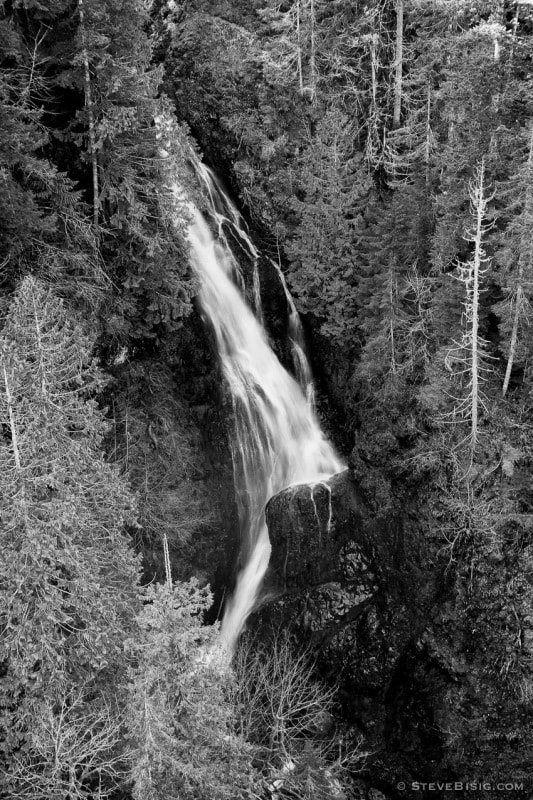 A black and white fine art landscape photograph of Vincent Creek Falls as viewed from the High Steel Bridge above the South Fork of the Skokomish River in rural Mason County, Washington. 